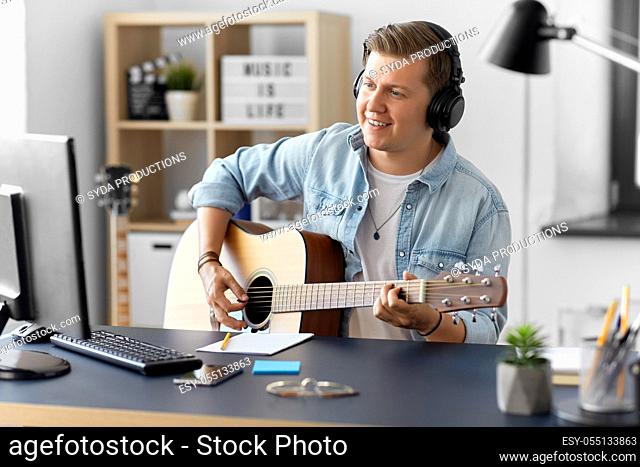 man in headphones playing guitar at home