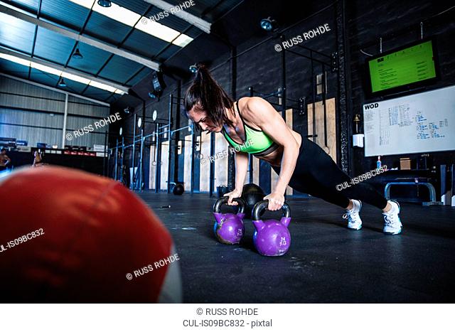 Woman exercising in gymnasium, using kettlebells