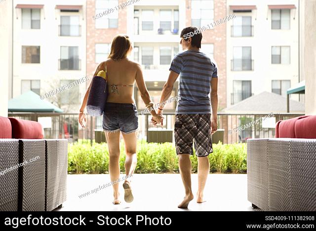 Couple wearing swimsuits walking and holding hands