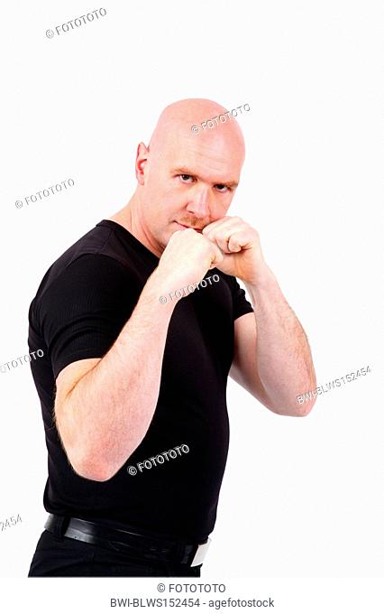 bald headed, young mean man threatening with his clenched fists