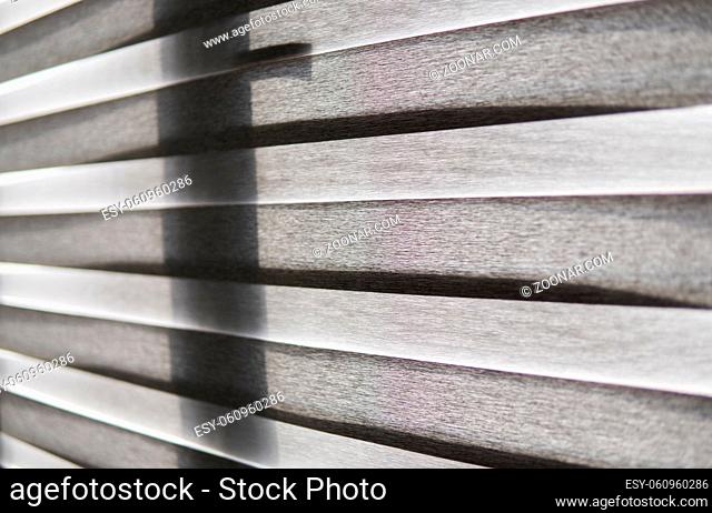 Details of brown fabric roller blinds on the plastic window with wood texture in the living room