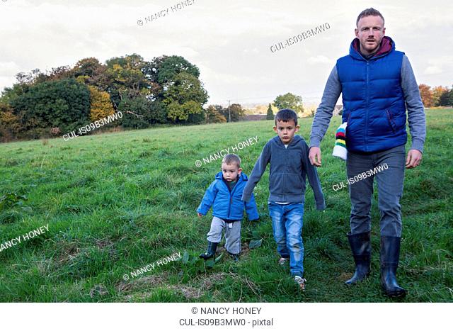 Father and sons walking in field