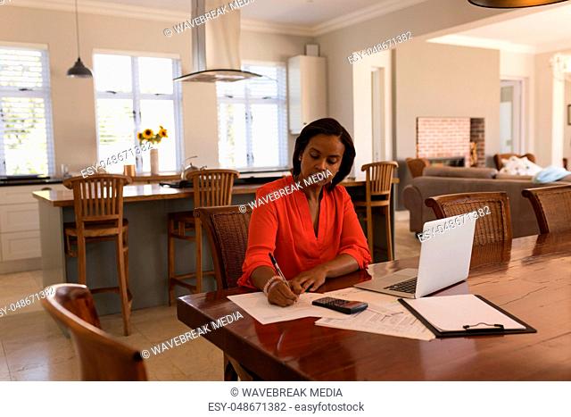 Woman calculating invoices at home