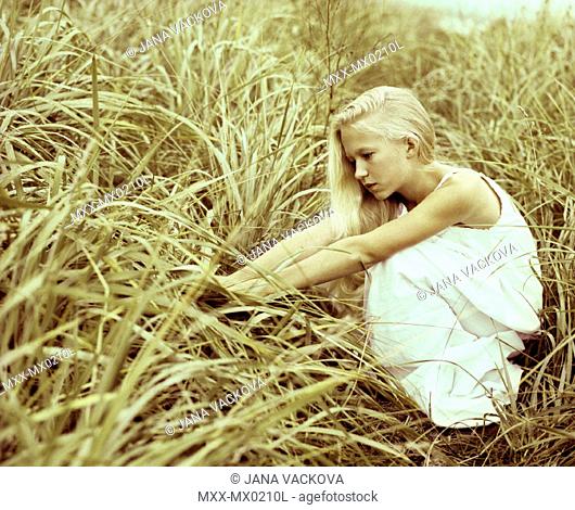 Girl crouching in long grass