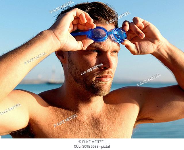 Swimmer putting on swimming goggles
