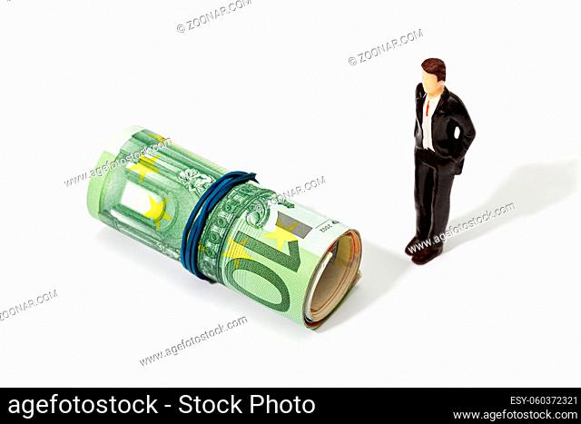 Human representation of a man looking at a Roll of money. Finance, investment or savings concept