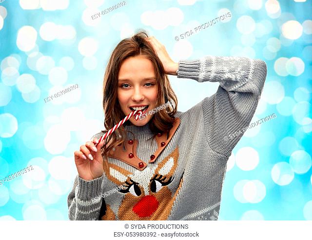 woman in christmas sweater biting candy cane