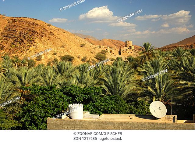 Dach eines Wohnhauses mit Wassertank und Satellitenantenne vor einem Wachturm beim Bergdorf Misfah al Abriyeen am Fuss der Hajar Berge, Wilayat al Hamra