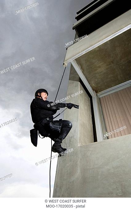 SWAT Team Officer Rappelling and Aiming Gun