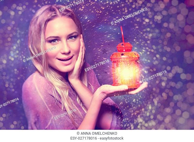 Portrait of a beautiful excited woman surprised of a glowing light in lantern, true miracle in Christmas eve, happy magical night