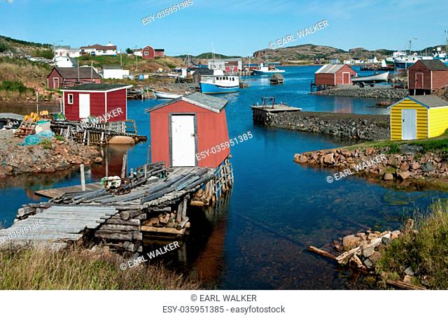Fishing shanties sit on rustic wooden piers and rock jetties that extend into a small harbor on the north coast of Newfoundland