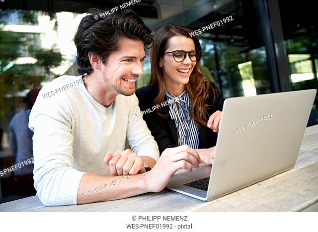 Happy businessman and businesswoman with laptop meeting in the city