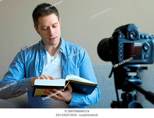Handsome man making video blog about books and education