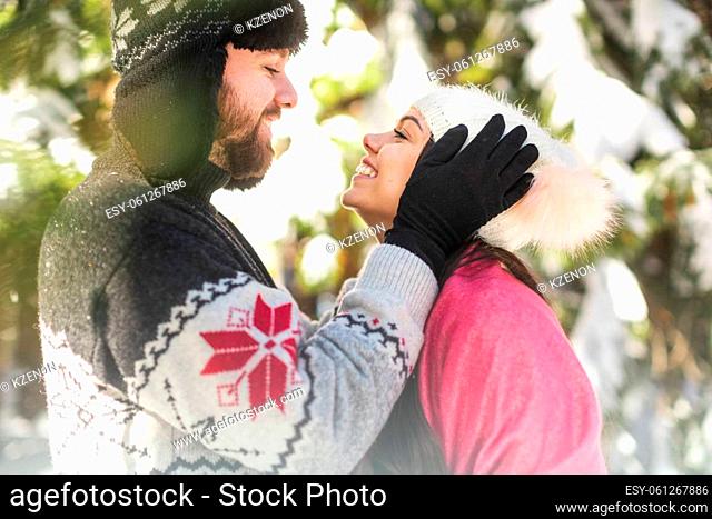 Portrait of happy couple laughing while looking each other in winter forest