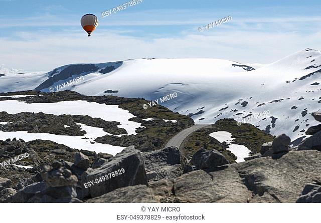 hot air balloon above the dalsnibba or road 63 touristic road to the high view of the geirangerfjord in norway with snow in summer on the tops of the mountains