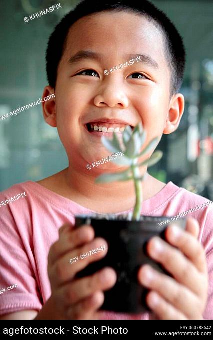 toothy smiling face of asian children holding succulent pot in hand