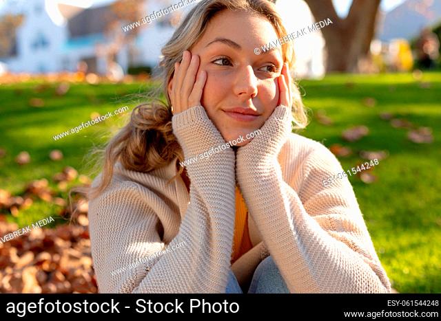 Happy caucasian woman smiling and looking away, sitting in garden