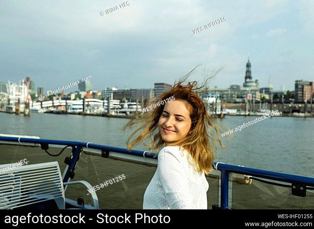Smiling woman with eyes closed sitting in ferry boat on sunny day, Hamburg, Germany