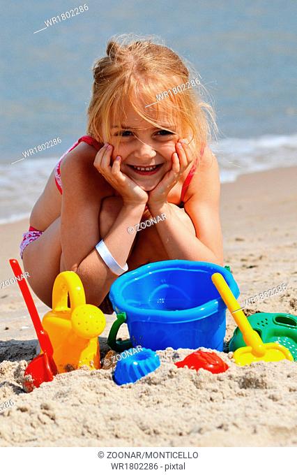 Little girl playing on the sand beach