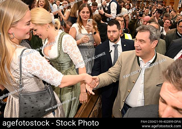 21 April 2023, Bavaria, Munich: Bavarian Prime Minister Markus Söder (CSU) (r) shakes hands with a female guest (l) in the Bayernland festival hall at the start...