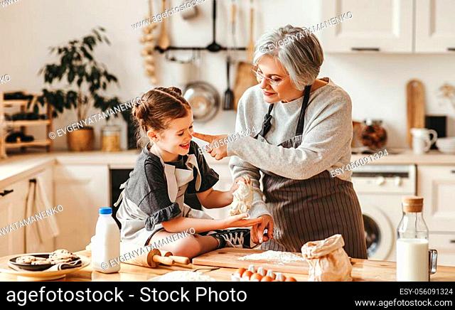 happy family grandmother and granddaughter child cook in the kitchen, knead dough and bake cookies