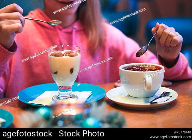 Girl eating a dessert and drinking a tea in coffee shop. Candid people, real moments, authentic situations
