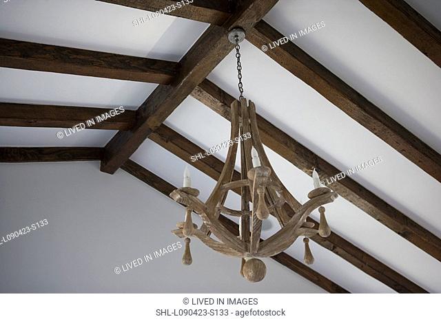 Detail wooden chandelier hanging from wooden ceiling beams