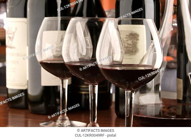Three red wine glasses and bottles