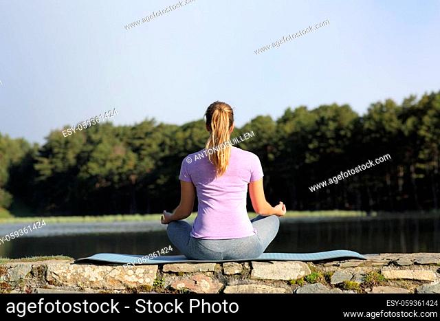 Back view of a woman doing yoga exercise in nature a sunny day