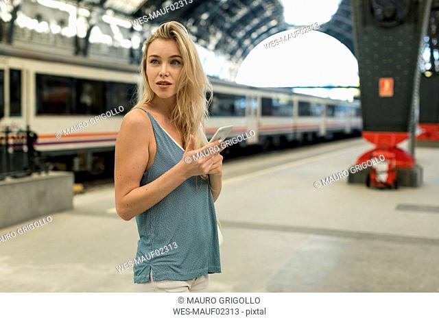 Young woman with cell phone at the train station looking around