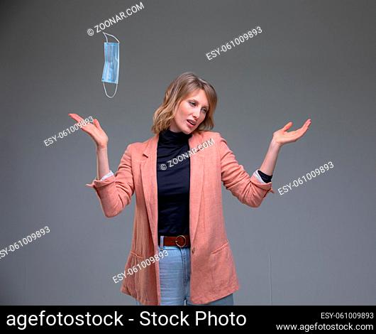 Head portrait attractive blond woman throws out her surgical mask protecting from virus. End of pandemia concept
