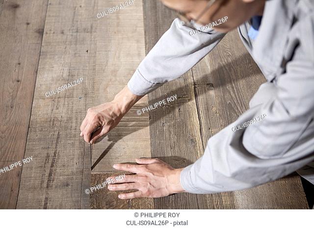 Carpenter checking quality of wood plank in factory, Jiangsu, China