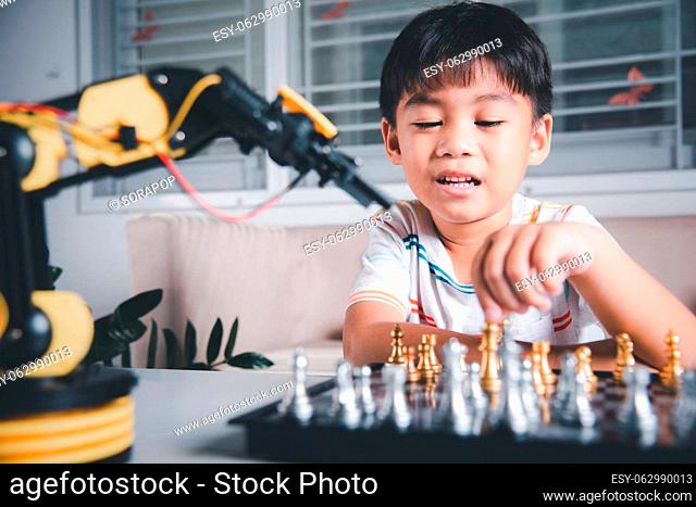 Asian little boy is playing chess with robot machine arm, STEM education E-learning, Funny children learning successful getting a lesson control robot arm