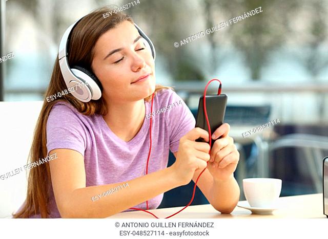 Portrait of a relaxed teen listening to music in a bar in the evening