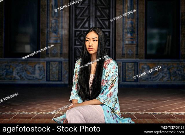 Portait of beautiful young woman sitting on steps wearing a kimono