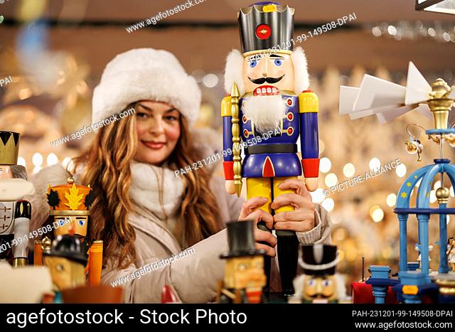 01 December 2023, Bavaria, Nuremberg: A stall vendor holds a nutcracker in her hands at the Nuremberg Christmas Market. The Nuremberg Christkind officially...