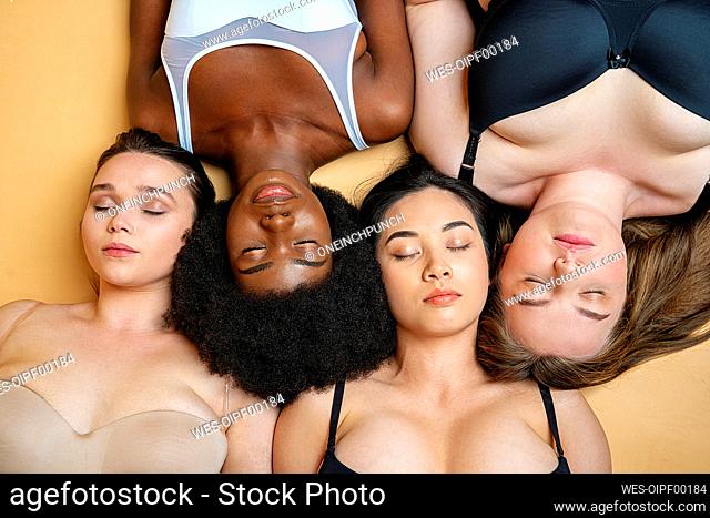 Young women wearing lingerie resting while lying on yellow background
