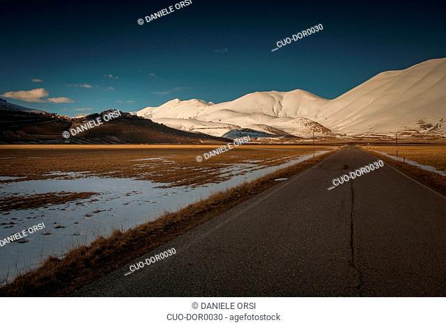 Mountain road with mountains in the background near Castelluccio di Norcia, Umbria, Italy