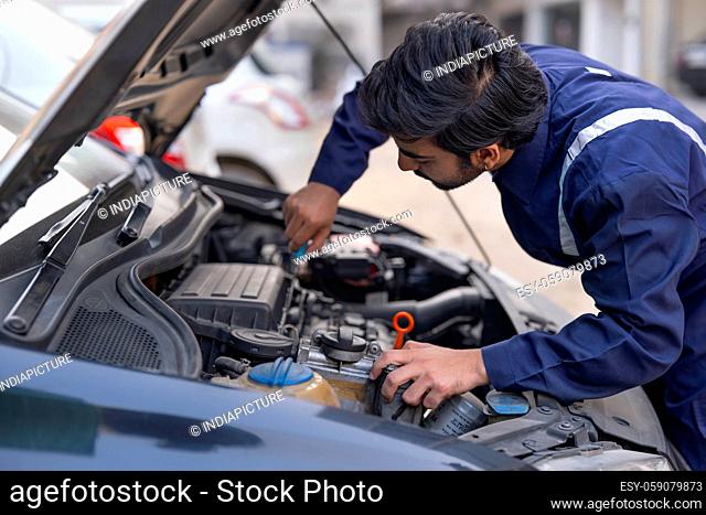 A YOUNG MECHANIC WORKING ON CAR ENGINE