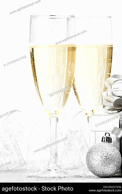 Two champagne glasses and christmas decoration on silver bokeh background