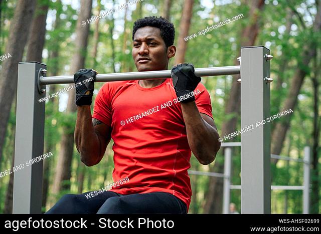 Sportsman exercising at high bar in the forest