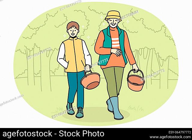 Smiling grandfather and grandson walking in forest with baskets. Happy granddad and grandchild look for mushrooms in wood together