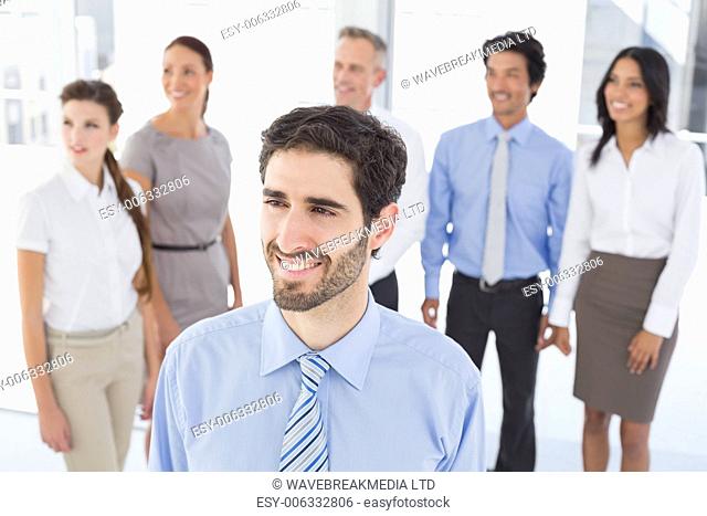 Business man smiling at work with staff behind him