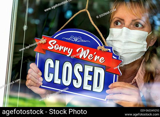 Female Store Owner Wearing Medical Face Mask Turning Sign to Closed in Window