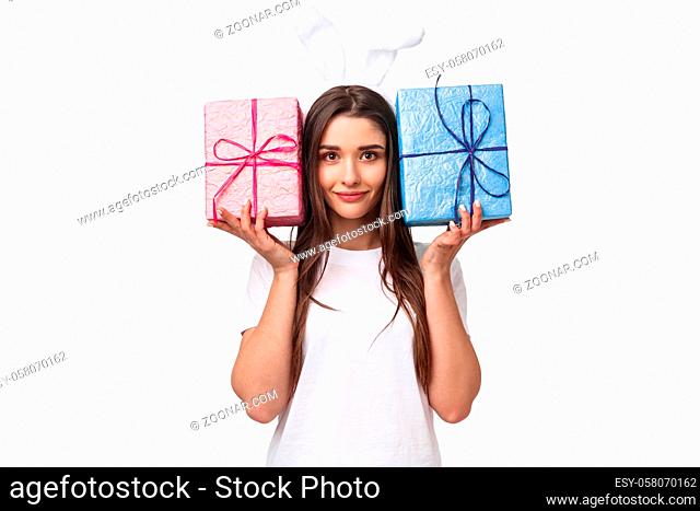 Celebration, holidays and presents concept. Portrait of adorable young woman in rabbit ears, holding two boxes with gifts, smiling camera