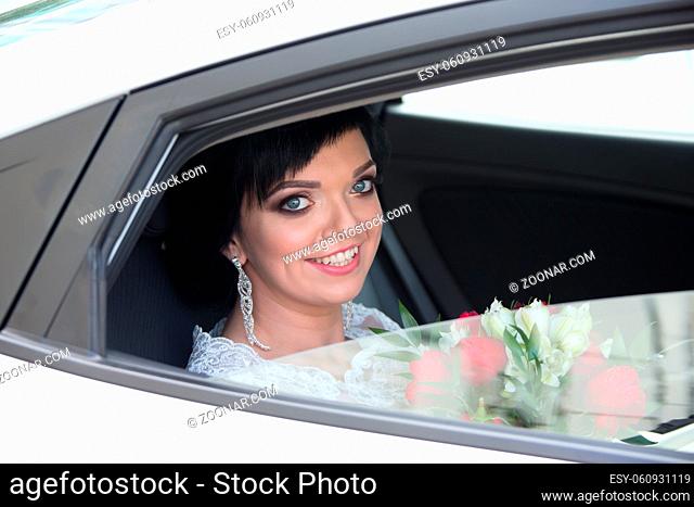Portrait of a bride in a car with a bouquet