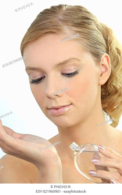 Young woman dabbing perfume onto her wrist