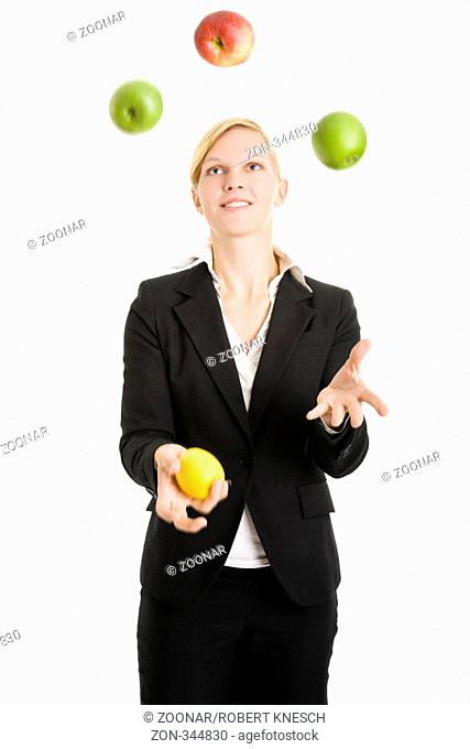 Blonde Frau im Jackett jongliert mit vier Äpfeln