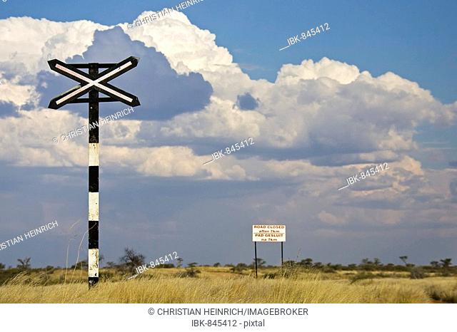 Warning cross in front of a railroad crossing, sign reading Road closed after 7 km, Namibia, Africa