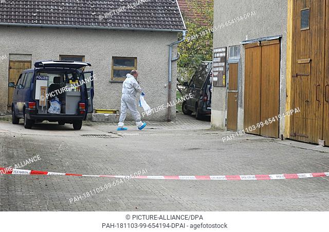 03 November 2018, Baden-Wuerttemberg, Laichingen: An employee of the police forensics department walks across a courtyard behind a barrier tape